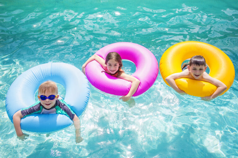 Group of kids playing on inflatable tubes in swimming pool