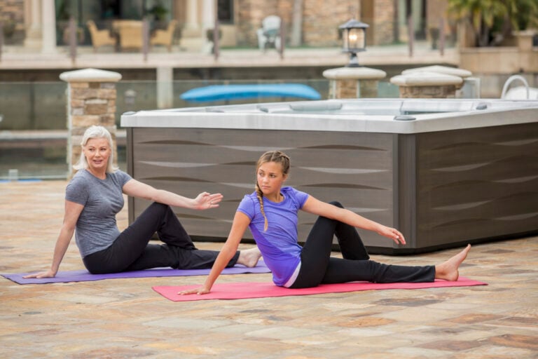 Grandmother and granddaughter doing yoga beside a hot tub - water yoga