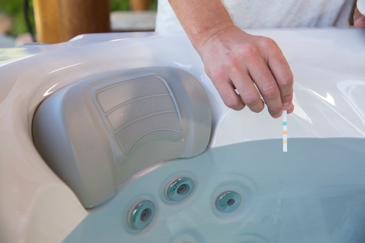 man dipping a pH test strip into his hot tub water - pH increaser for hot tubs