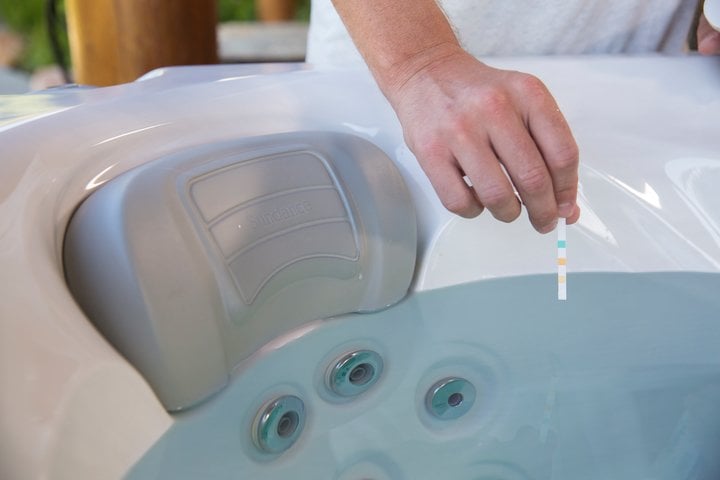 preventing hot tub rash - man checking water chemistry with pH test strips