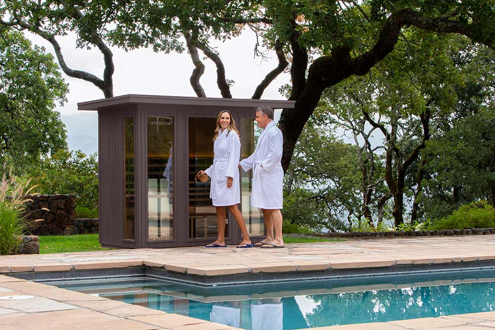 clearlight outdoor home saunas - couple stepping into their poolside sauna