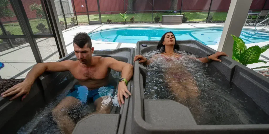 Two people relax in adjacent outdoor hot tubs next to a backyard pool.”] }? Wait need proper array. Let's compose.