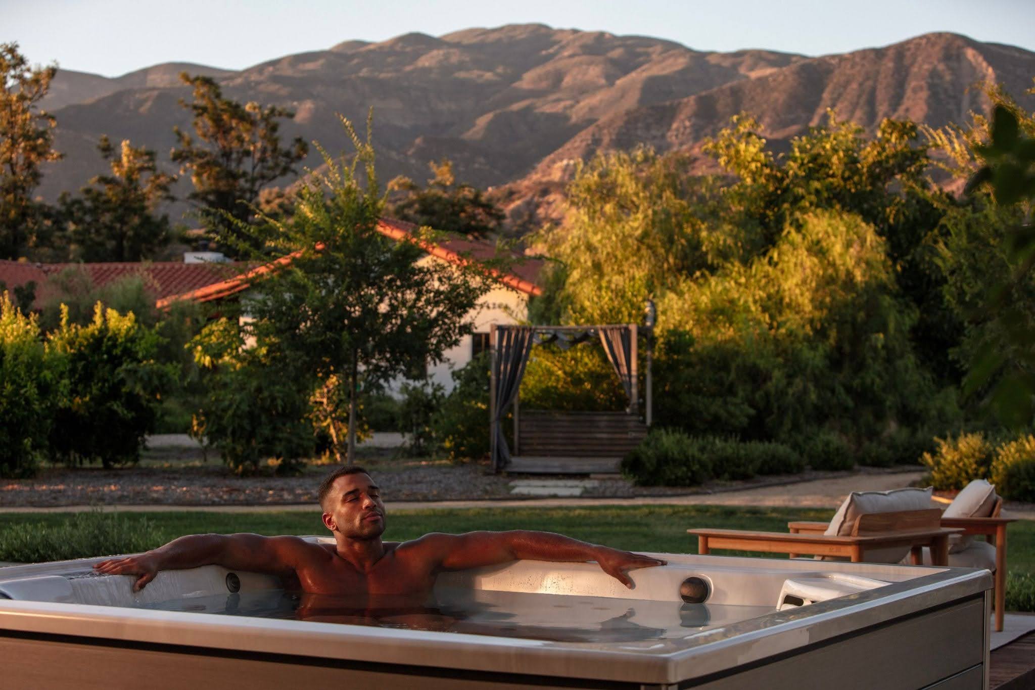 Man in hot tub with mountains in background